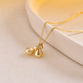 A miniature yellow gold Lemon charm and Pear charm on a yellow gold rolo chain.